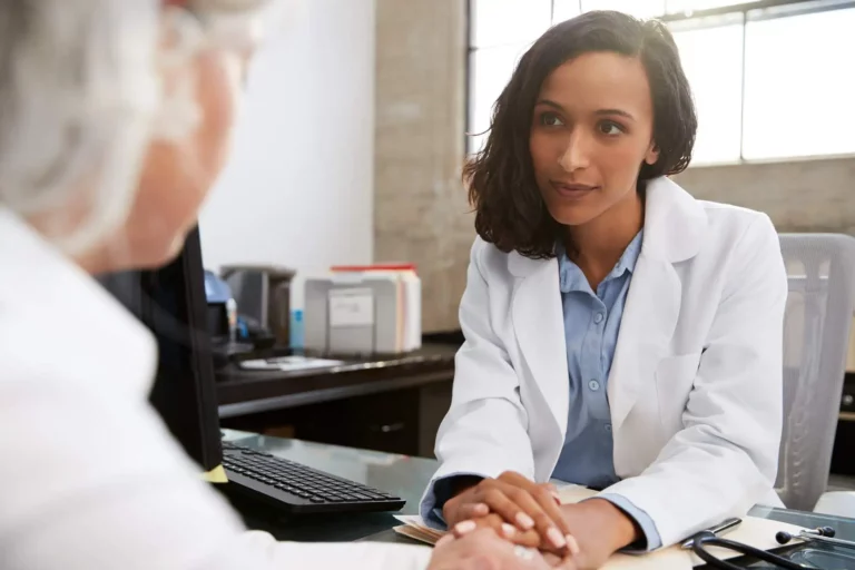 Photo of female doctor with empathetic expression talking to older woman across a desk