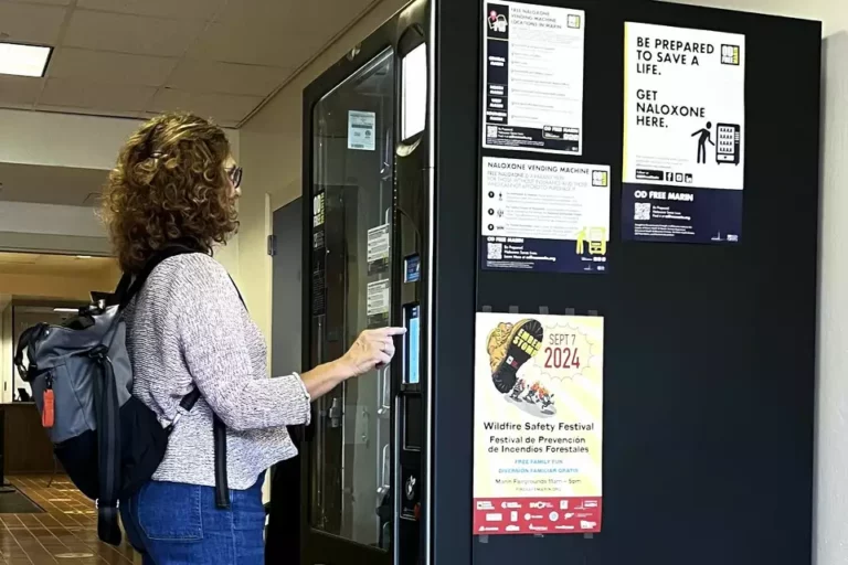 photo of a woman using a vending machine that disperses Naloxone