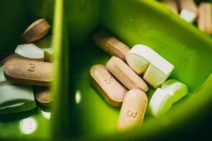 groups of pills of different colors and shapes in a plastic container