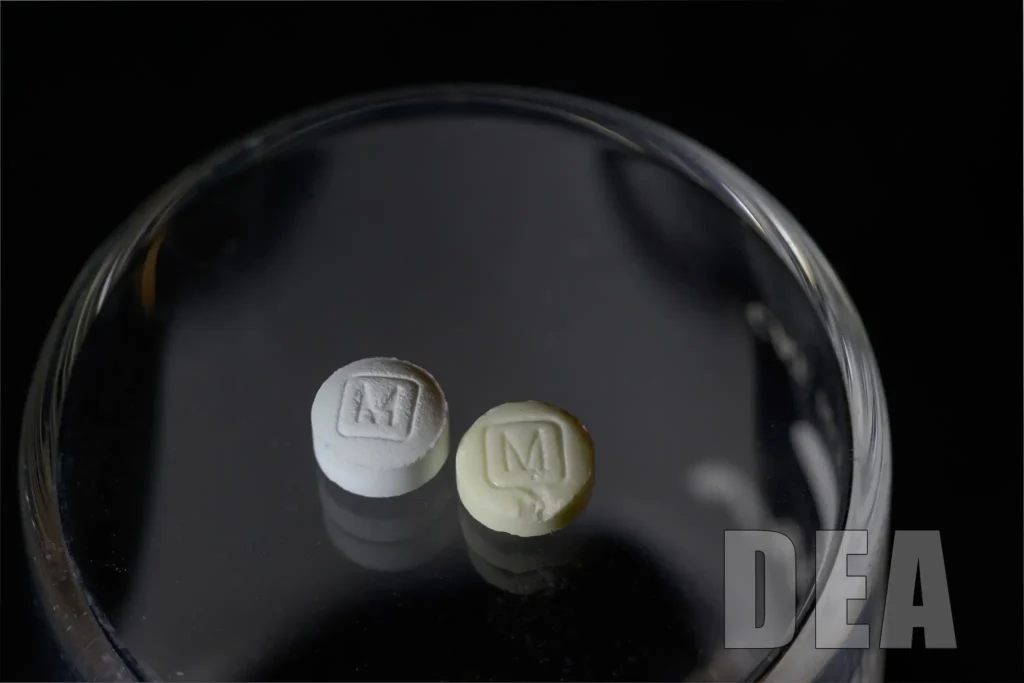 2 pills in a glass tray - comparison between authentic (left) and counterfeit (right) 30mg oxy.