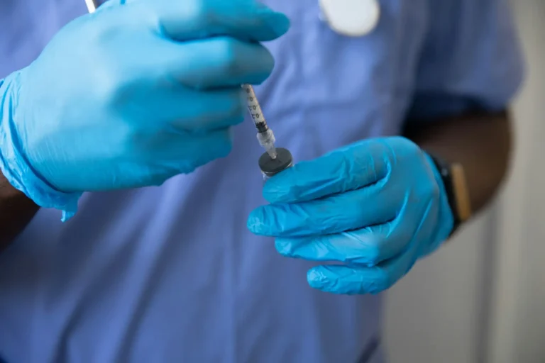 closeup of syringe being filled by man wearing gloves